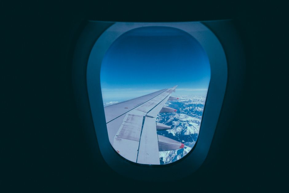 Airplane wing and snowy mountains seen through a window