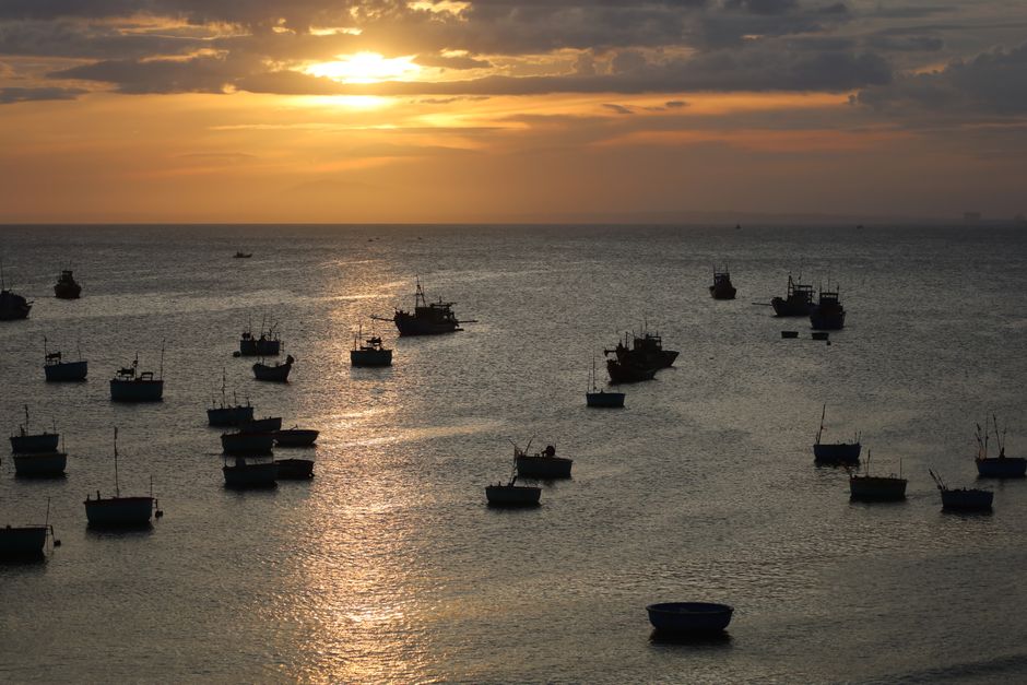 Tranquil ocean view with boats silhouetted against a vibrant sunset